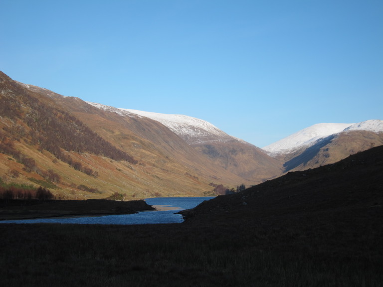 Snow covered peaks of the mountains with Loch na Leitreach in the foreground in Glen Elchaig
